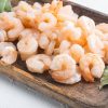 Boiled peeled prawns set, on wooden tray, on white stone  background