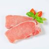 two slices of raw pork tenderloin with tomatos and basil on a white background
